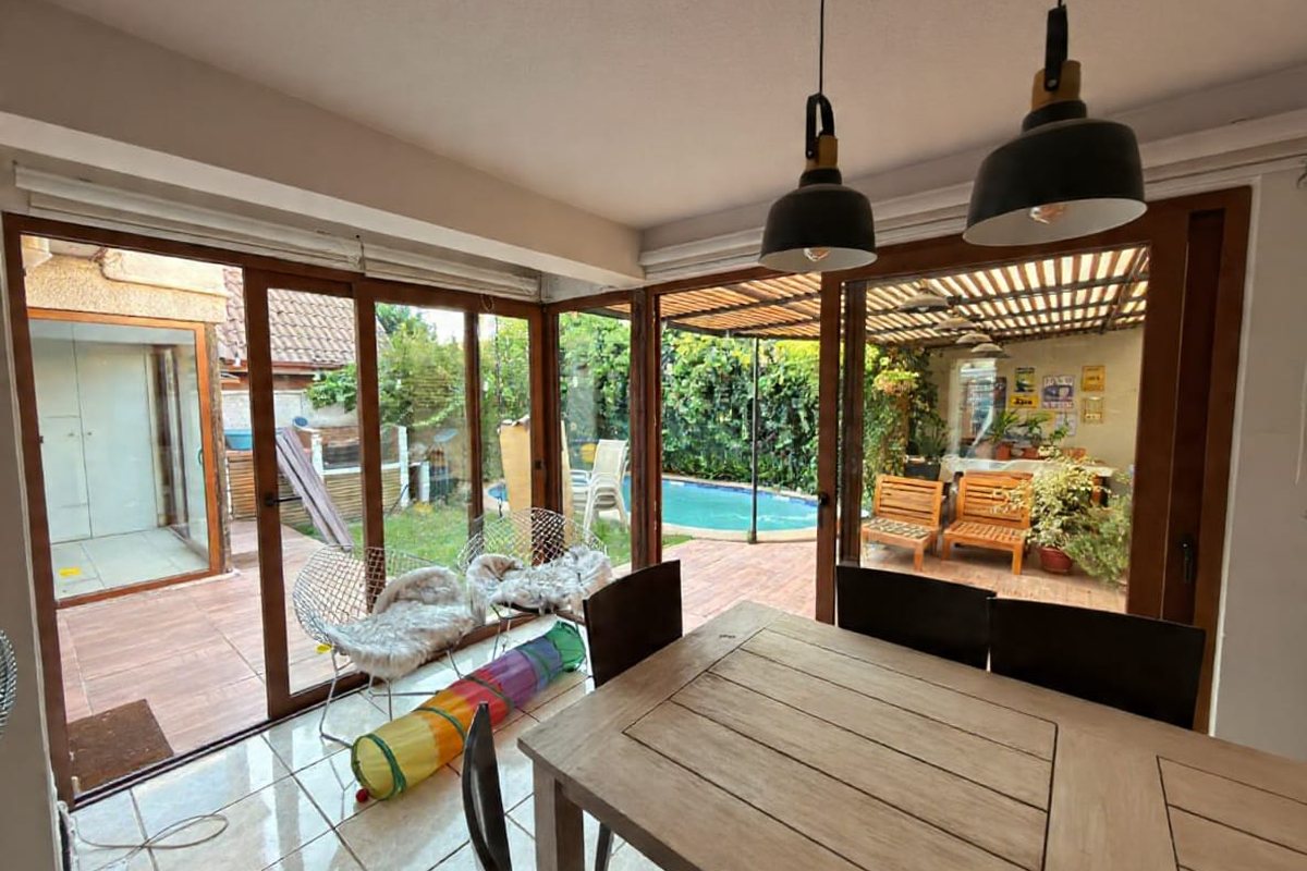 Comedor con puertas correderas de PVC abiertas hacia patio con piscina