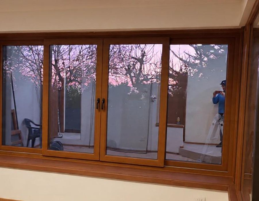 Ventana plegable de aluminio color madera al atardecer